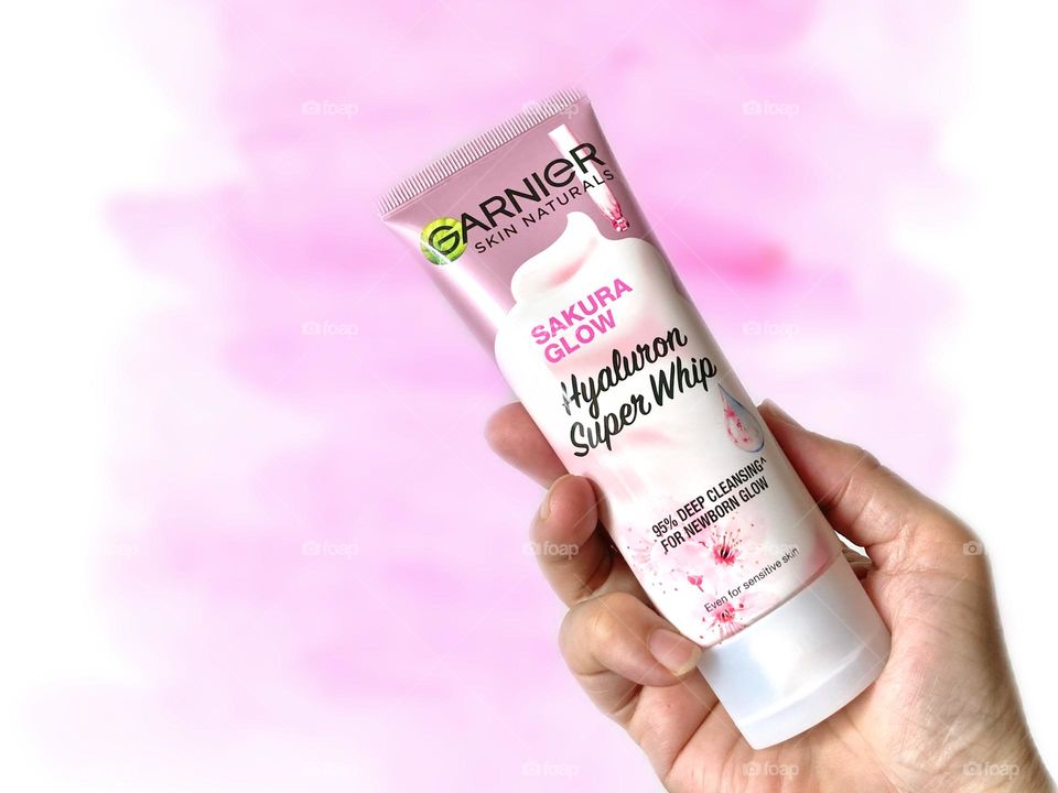 Background and copy space. Hand holding a tube of the Garnier Hyaluron Super Whip against pink background 