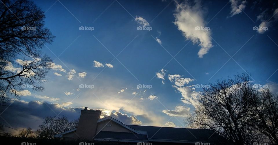 Here in this picture we have a beautiful blue skies with white clouds a house and a tree. enjoying the Beautiful outdoors.