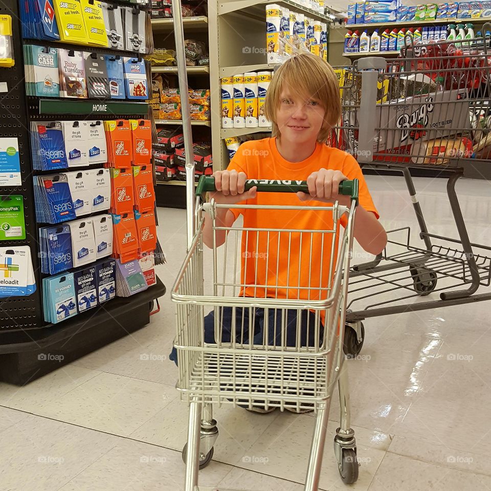 Boy with empty trolley in supermarket