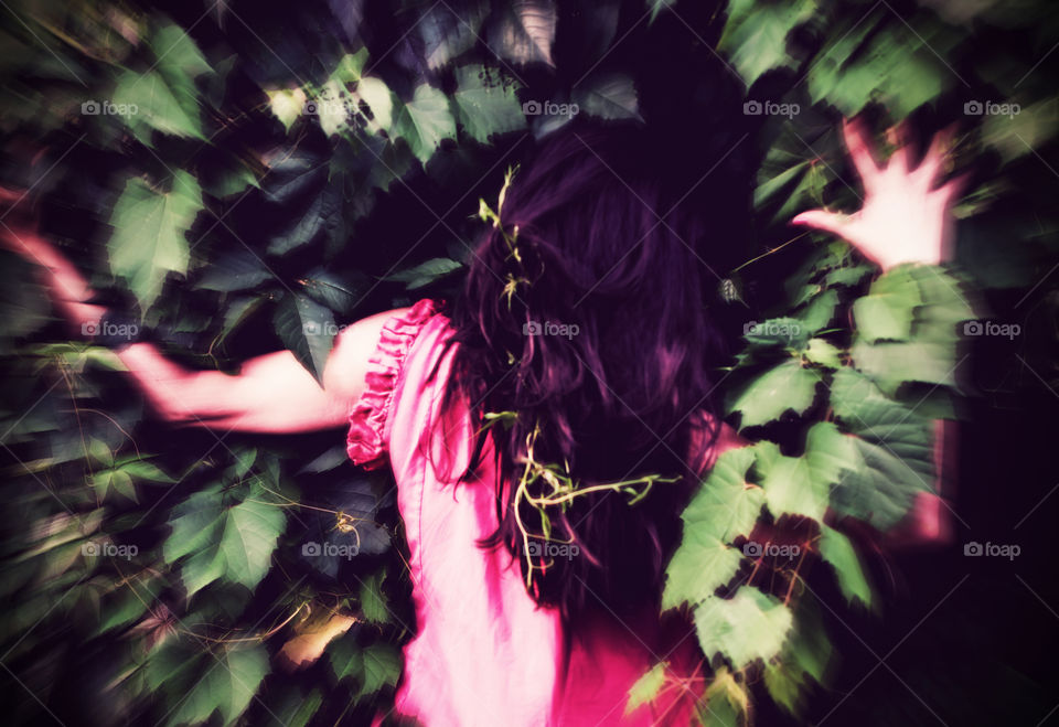 Woman in nature against wall of vines with vines in hair and blurred focus technique abstract background photography 
