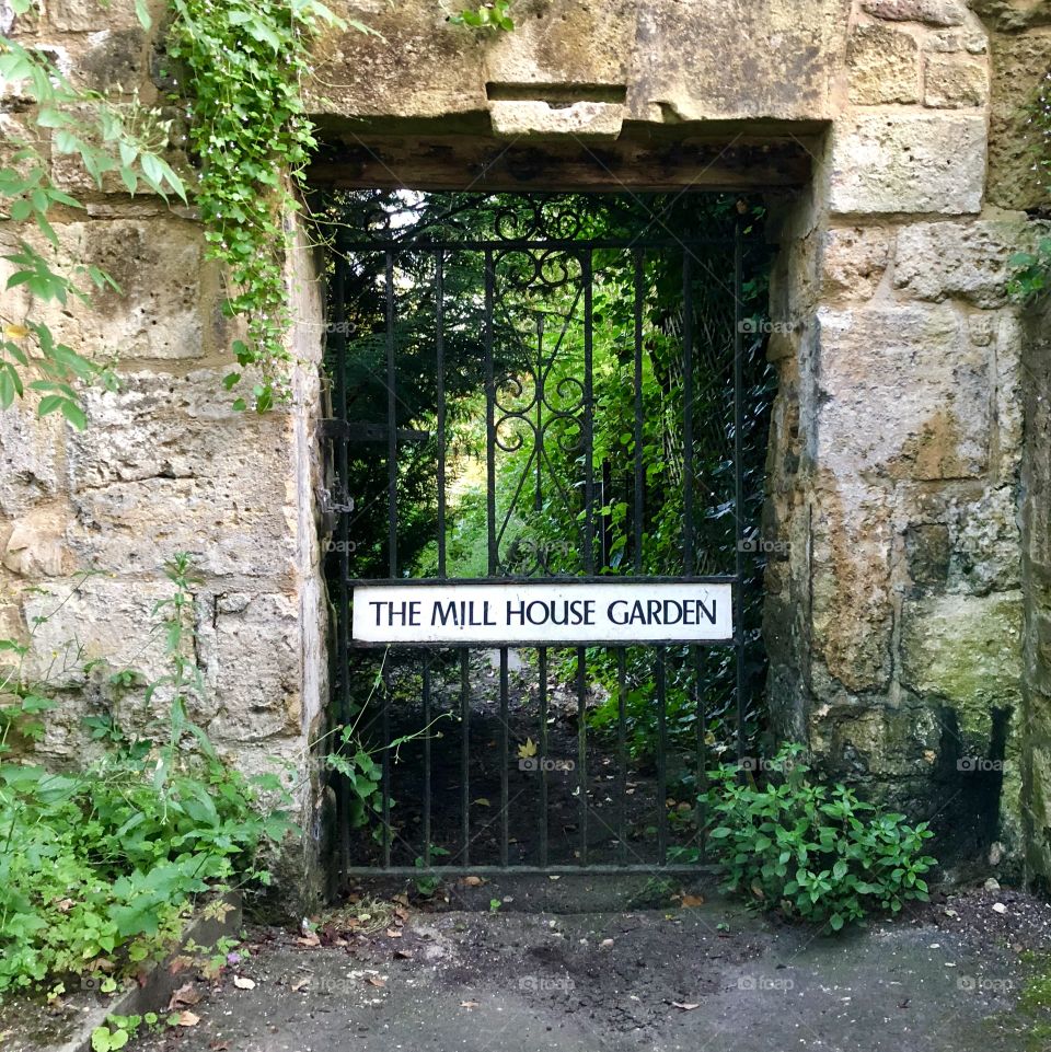 Metal Gate with sign to garden in stone wall 