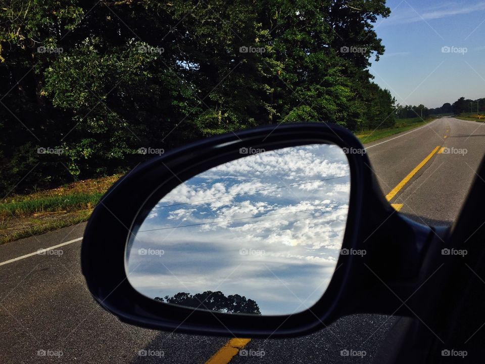Clouds reflected in car side mirror