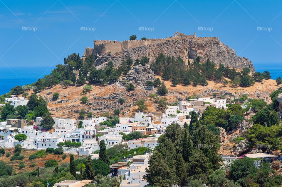 Remains of ancient Lindos Acropolis and medieval castle build on top of it on cliff rock. Below is a picturesque Lindos village with whitewashed houses. Lindos. Island of Rhodes. Greece. Europe.