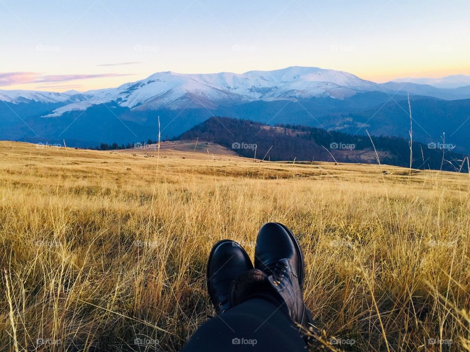 Black boots and mountains covered in snow in the background 
