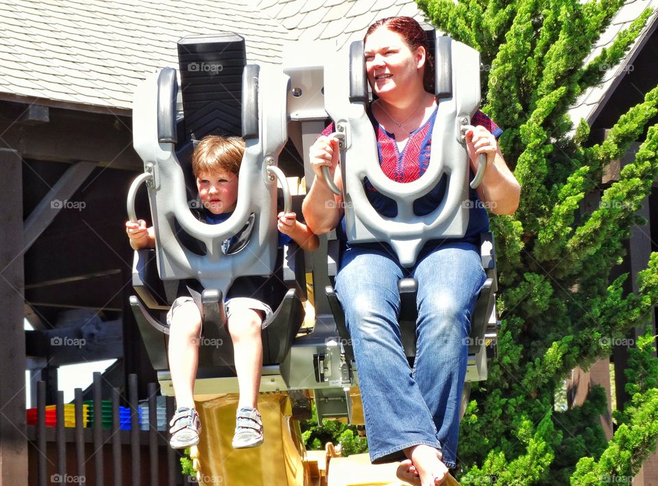 Mom And Son On Rollercoaster. Mother And Young Son Riding Amusement Park Thrill Ride
