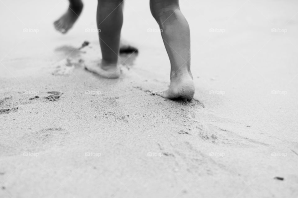 kids footprints in sand. kids playing on beach and leaving footprints on sand near water,monochrome photo