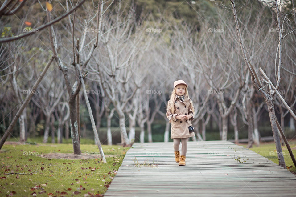 Stylish little girl walking in the autumnal park 