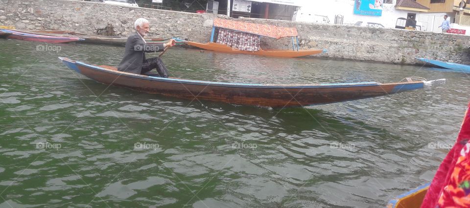 Boatman taking his own "Shikara " towadrs his House boat which remains in the waters of Dal Lake