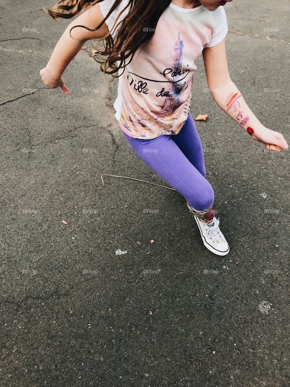 Young girl with bright purple pants and Converse sneakers on dancing in the parking lot and living life. 