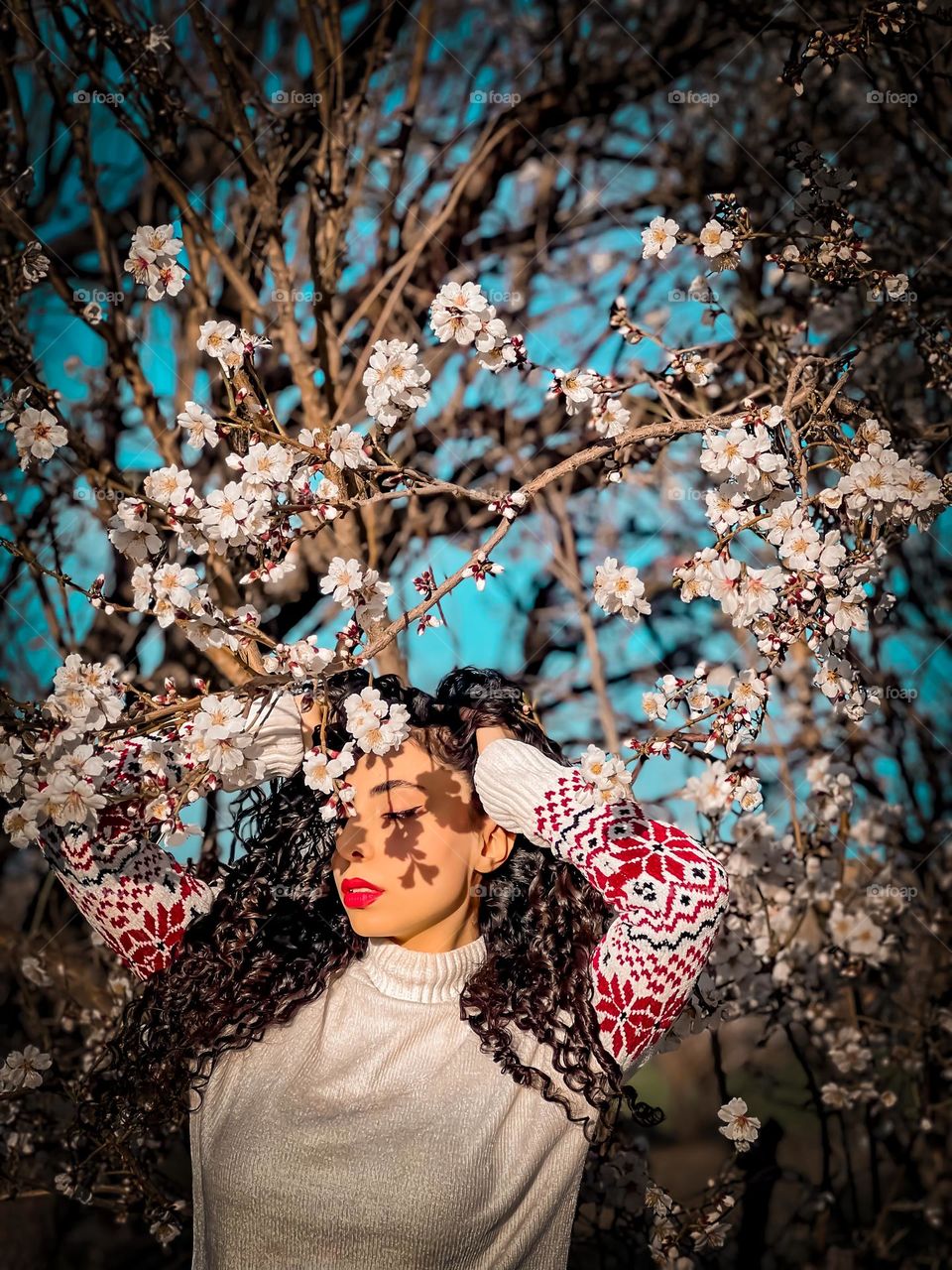 Curly-haired girl and blossoms in the spring air