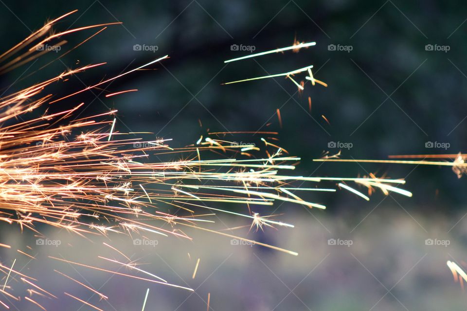 Side view of sparks from a bench grinder being used on a steel part