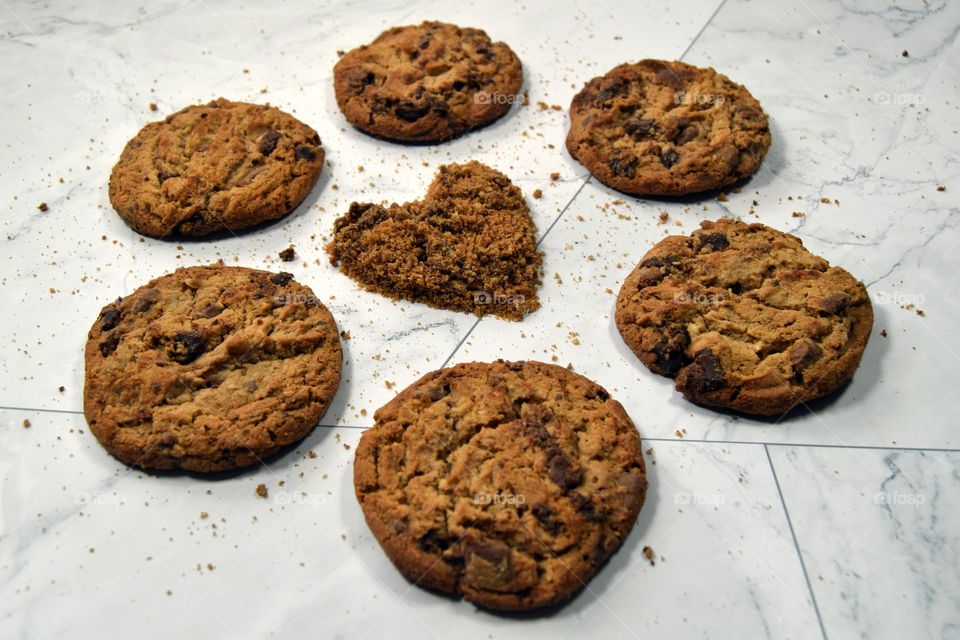 A simple heart formed using chocolate chip cookie crumbs surrounded by tasty golden brown chocolate chip cookies.