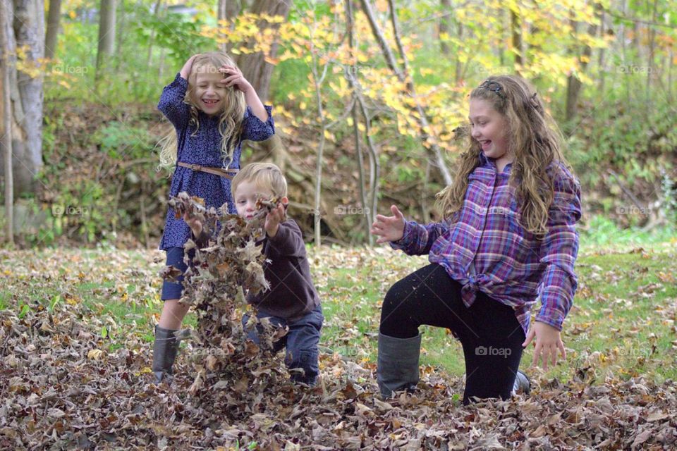 Children playing in park with dry leaves