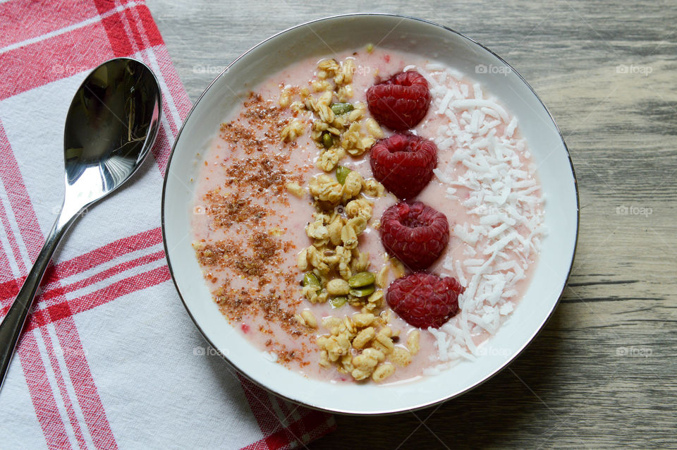 Fresh fruit smoothie bowl with flaxseed, raspberries, granola and coconut shavings