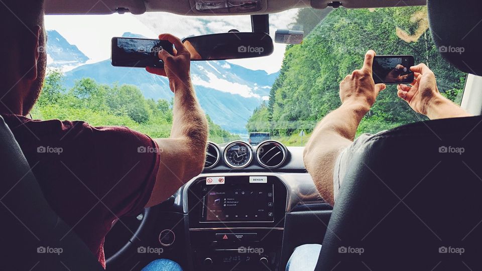 Taking pictures of magnificent nature with smartphones while driving high in the mountains in Norway. 