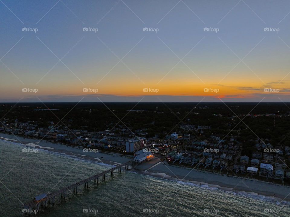 Incredible sunset casting golden hues against the new pier on the beach as the ocean waves crash on the shore 