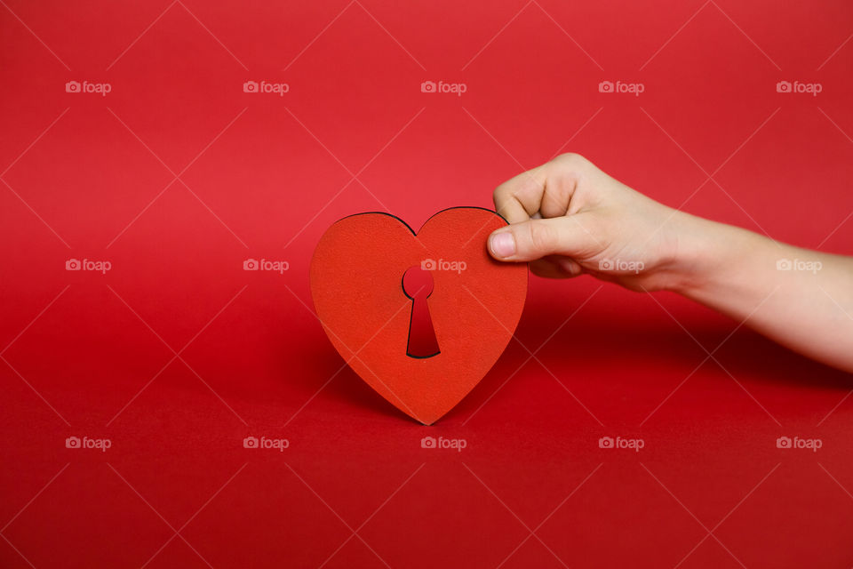 Human hand holding heart with red background