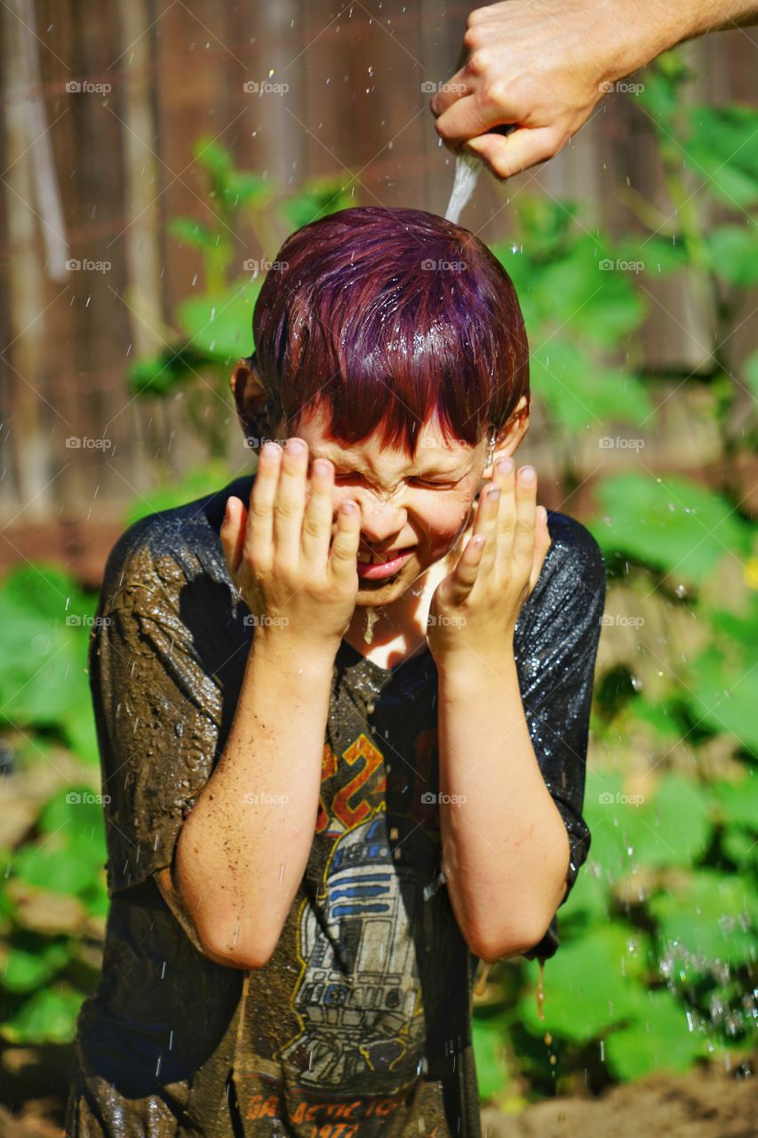 Boy Sprayed With Water In Summer