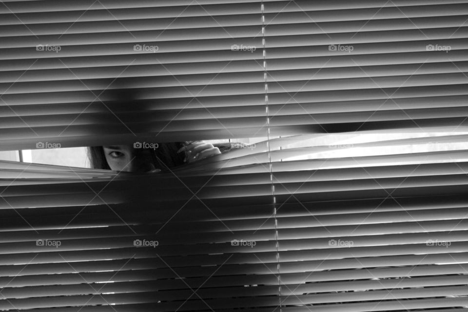 Woman peeking through blinds