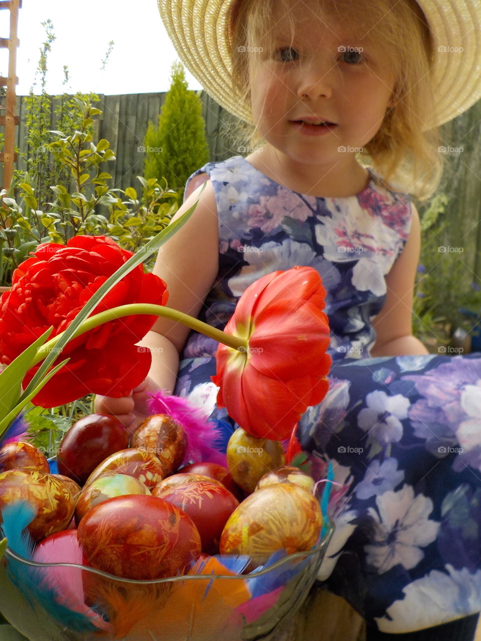 Little girl with easter eggs and red flowers