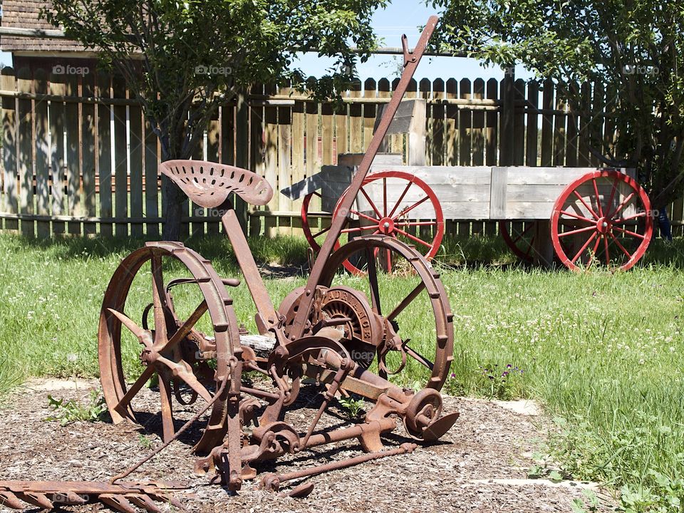 A rusted old field plow being used as an ornamental garden decoration in Central Oregon on a sunny summer day. 
