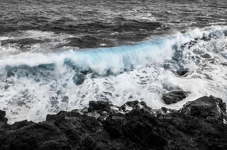 Wave coming to meet the lava rocks