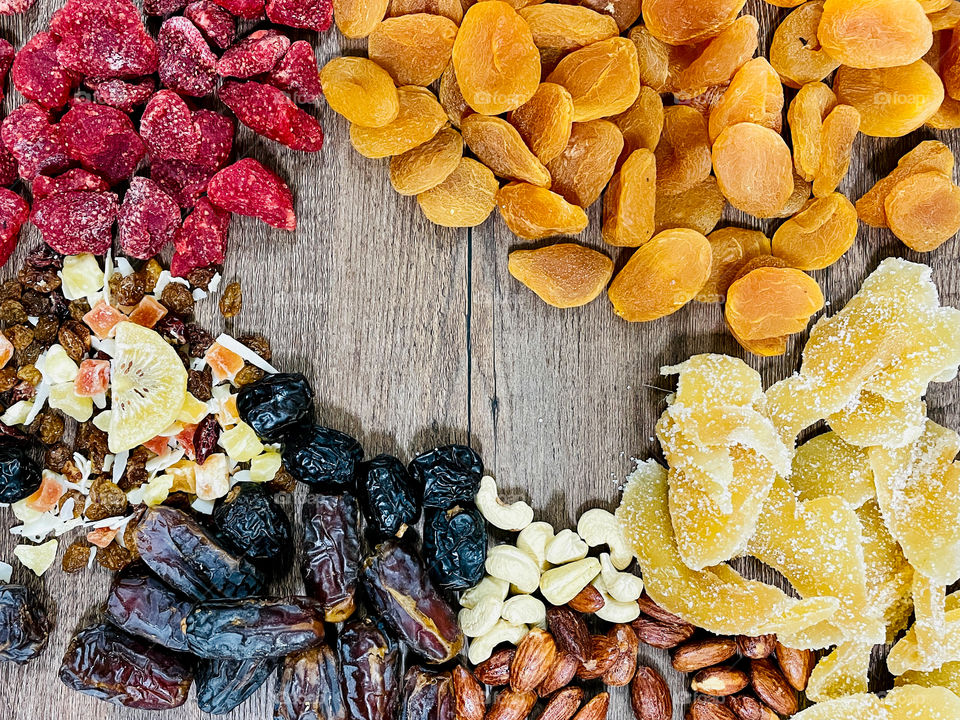 Your best flat lays. Dried fruits on a wooden table. Dates, strawberry, apricot, ginger, almond, cashews, mixed fruits,  kiwi