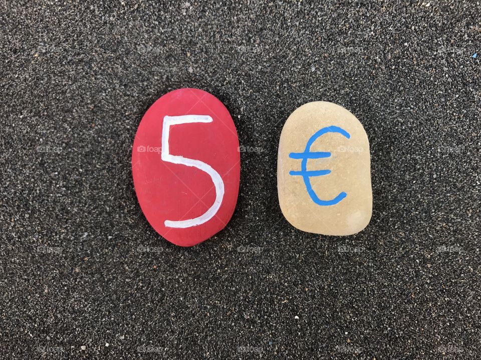 5 Euro with colored stones over black volcanic sand