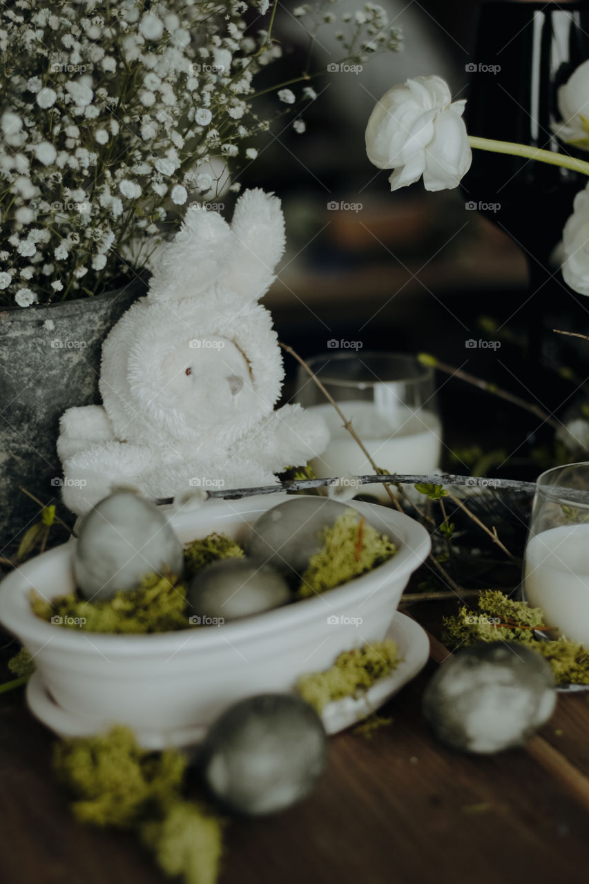 Easter bunny and white plate with grey dyed eggs on it, served Easter table