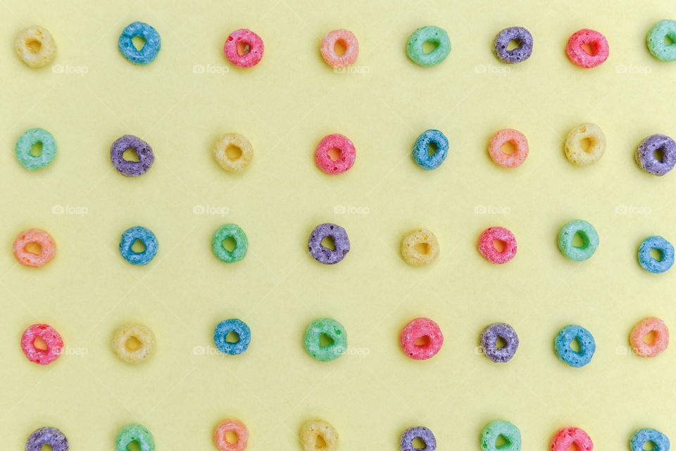 Colorful cereal rings spread out across a yellow background