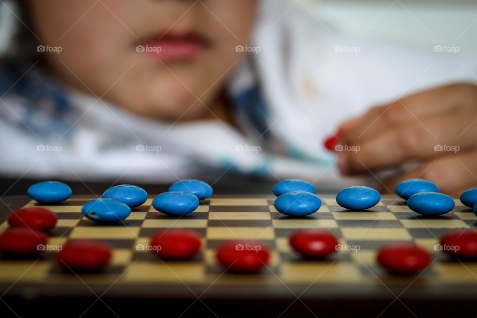 Child is playing checkers using M&Ms candies