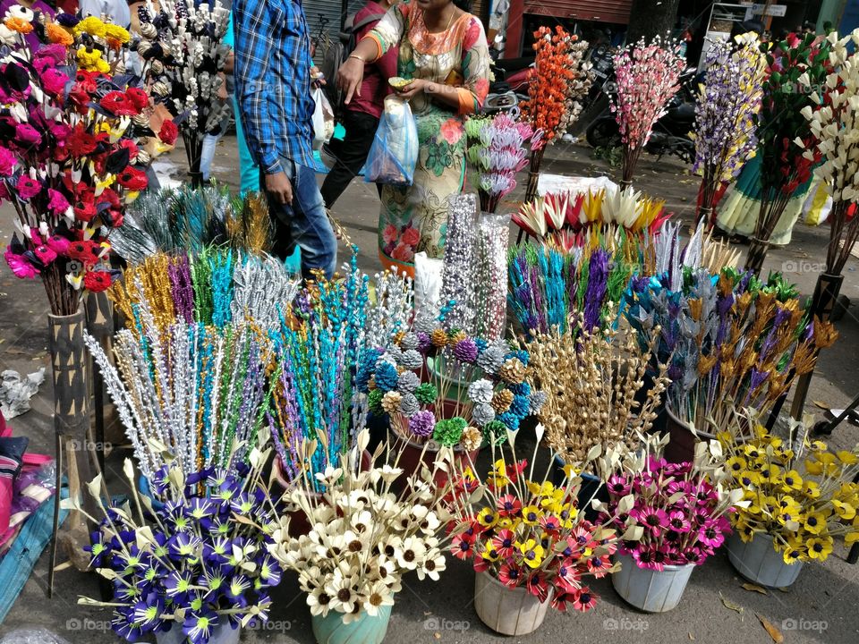 Woman buying artificial flowers from market stall
