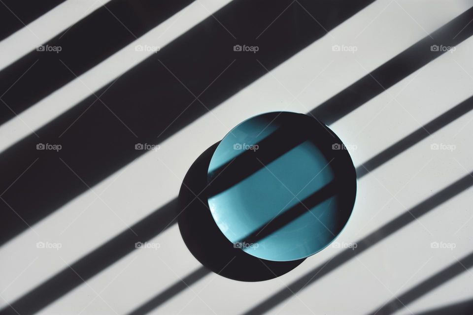 Minimalistic flat lay of plate only, covered with games of light and shadow 