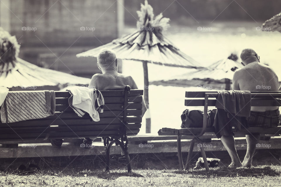 Elder male friends talking while sitting on the bench