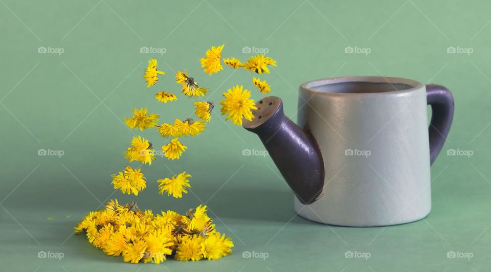 A small watering with streams of yellow flowers coming from its spout