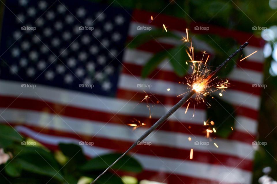 Sparkle USA. A sparkler in front of an American flag that's hung in a tree