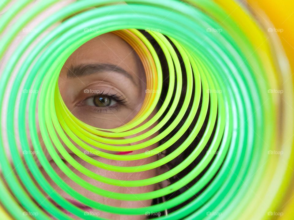 Circle, A Woman Looks through Rainbow Spring Toy