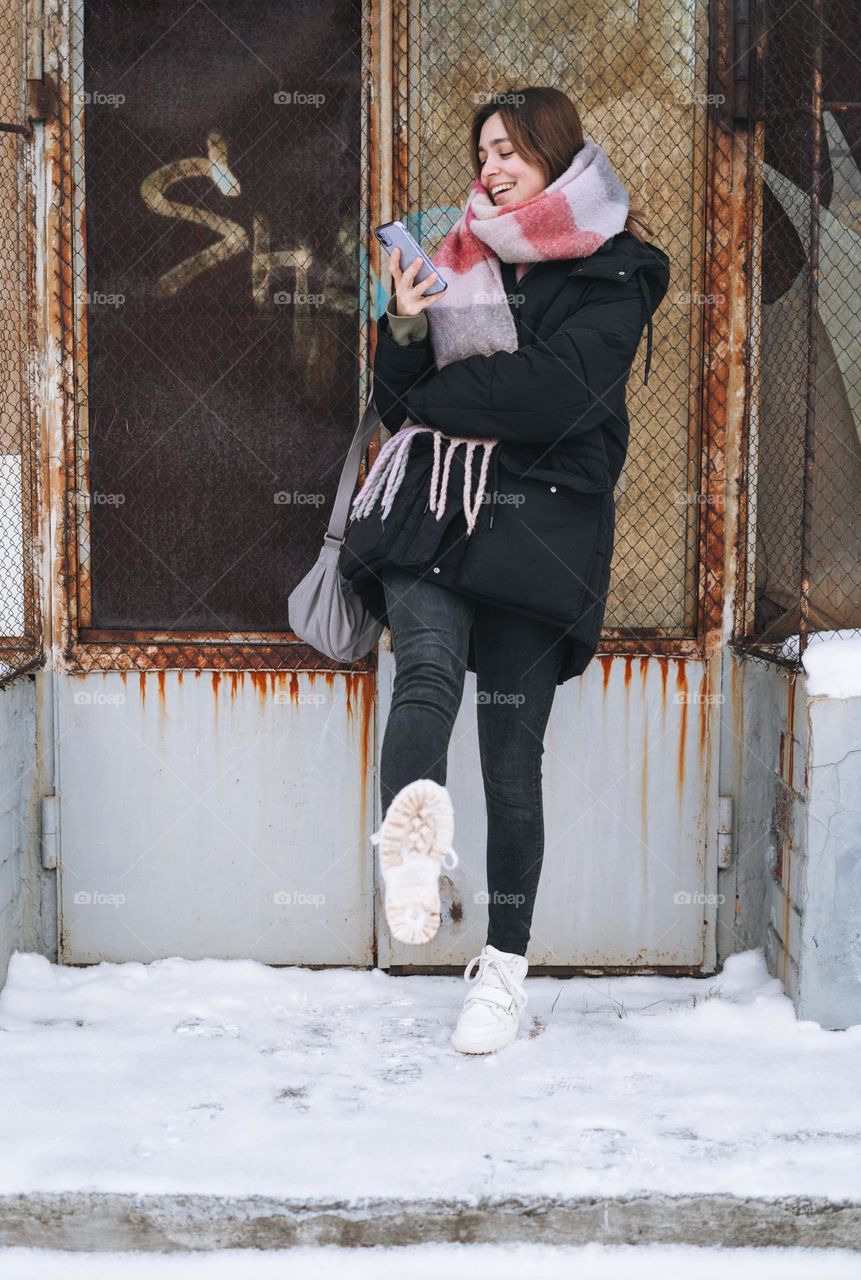 Young woman with mobile phone in white Dr. Martens boots in winter 