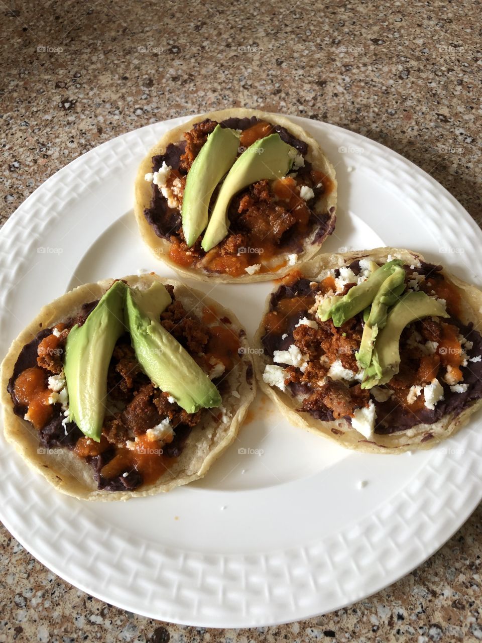 A beautiful and delicious homemade Mexican breakfast with fresh cheese, avocados, meat, beans, and corn tortilla. 