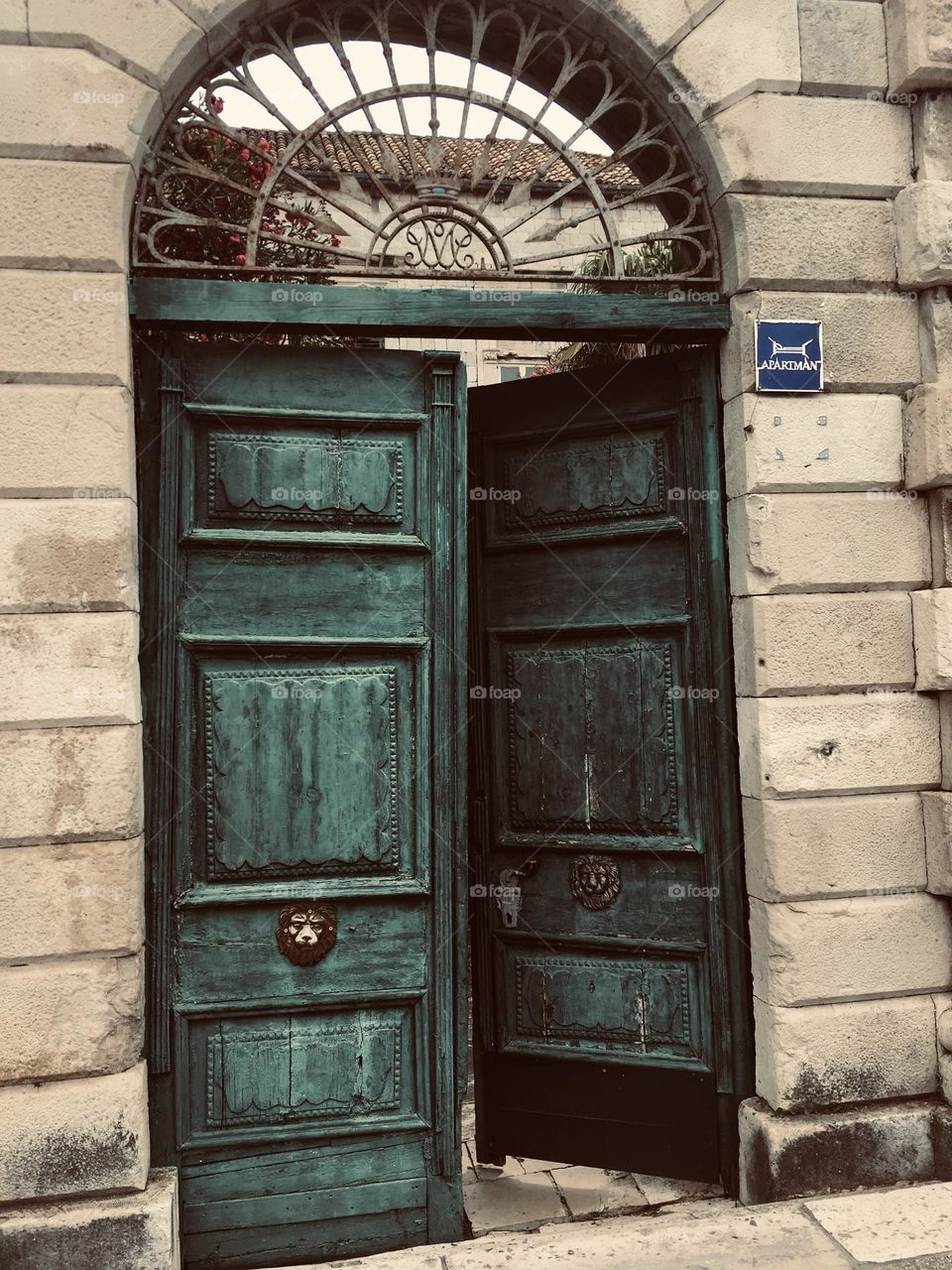 An antique wooden green door leading to an old palace from long ago.