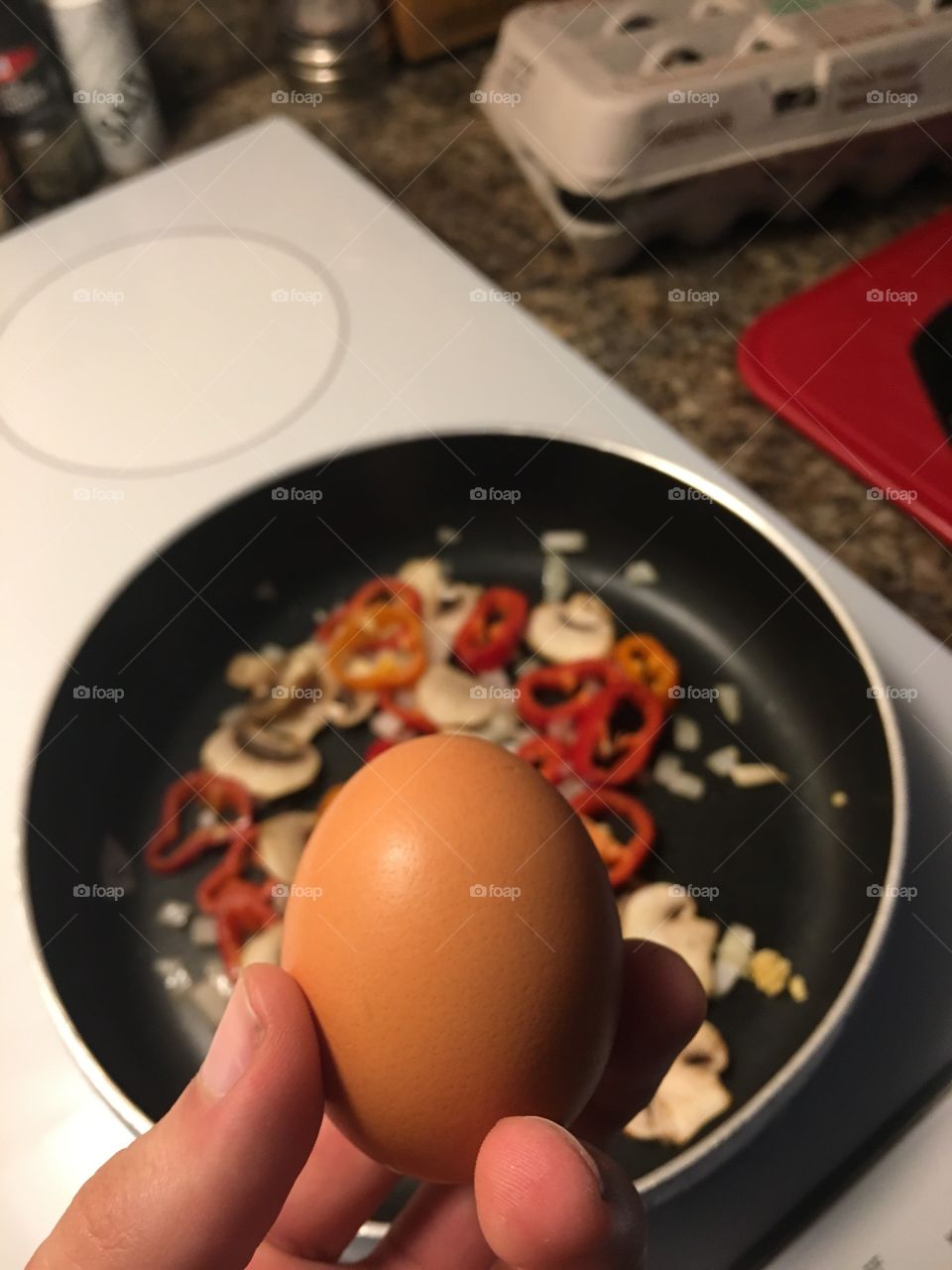 Holding food. An egg. Before being cracked to scramble with some onion mushrooms and peppers. 