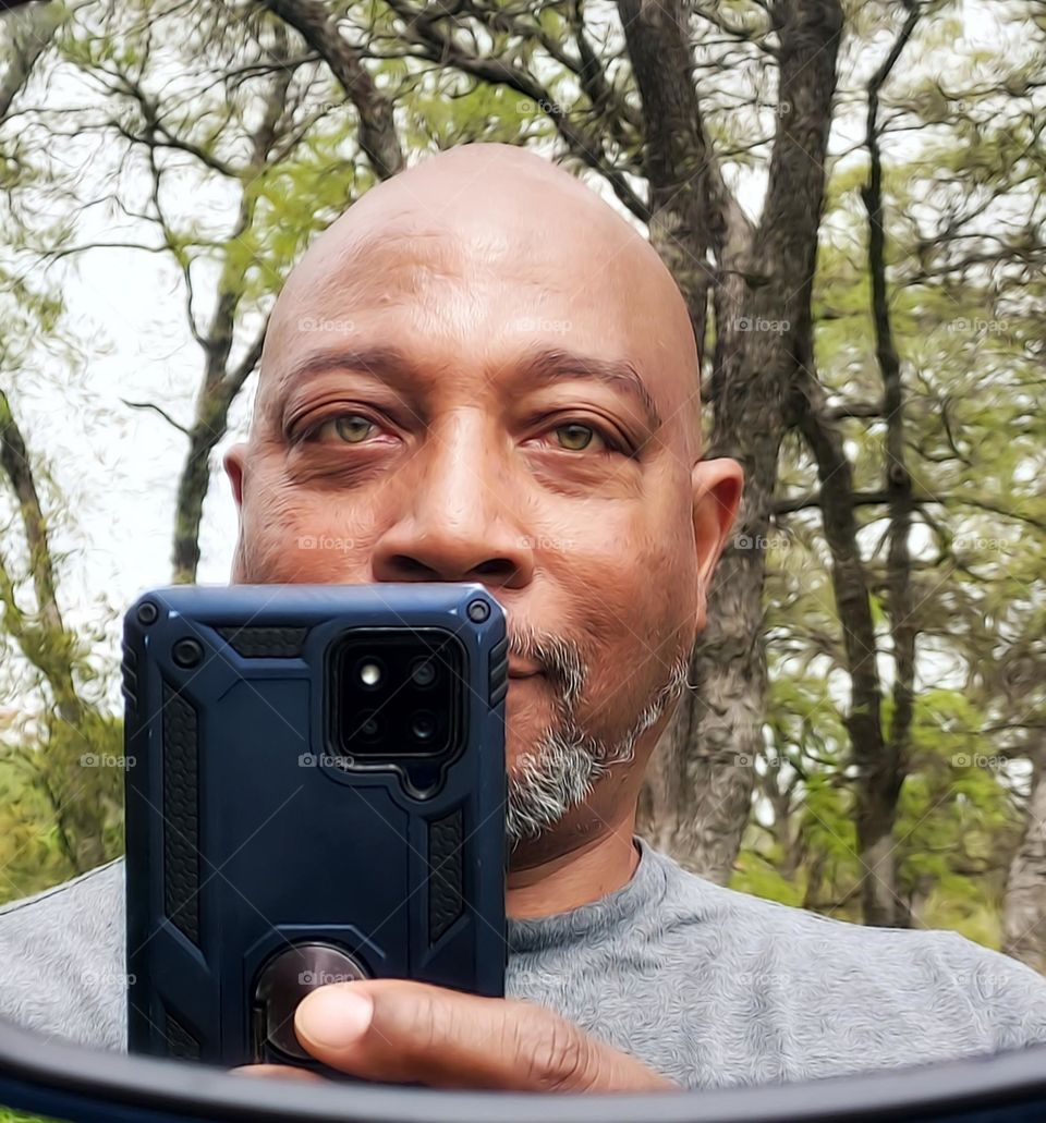 mirror reflection of a bearded man on a nature hike
