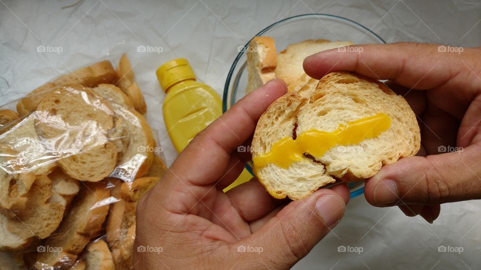 Mãos preparado Torradinhas, (fatias torradas de pão francês) com mostarda. 5/6