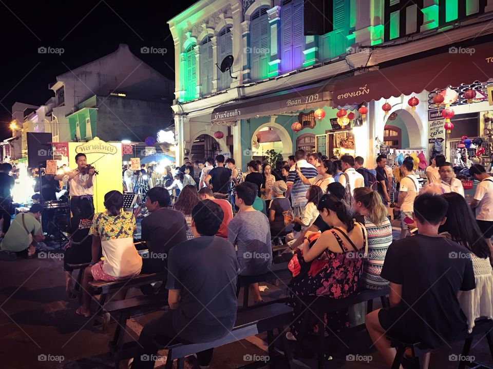 Audiences watching violin performance at Lardyai night walking street market in Phuket downtown, popular resort city of southern Thailand