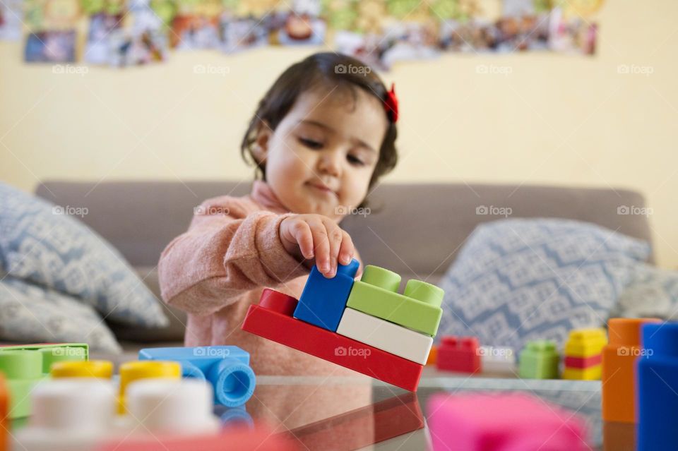 little girl playing rectangular colored constructions