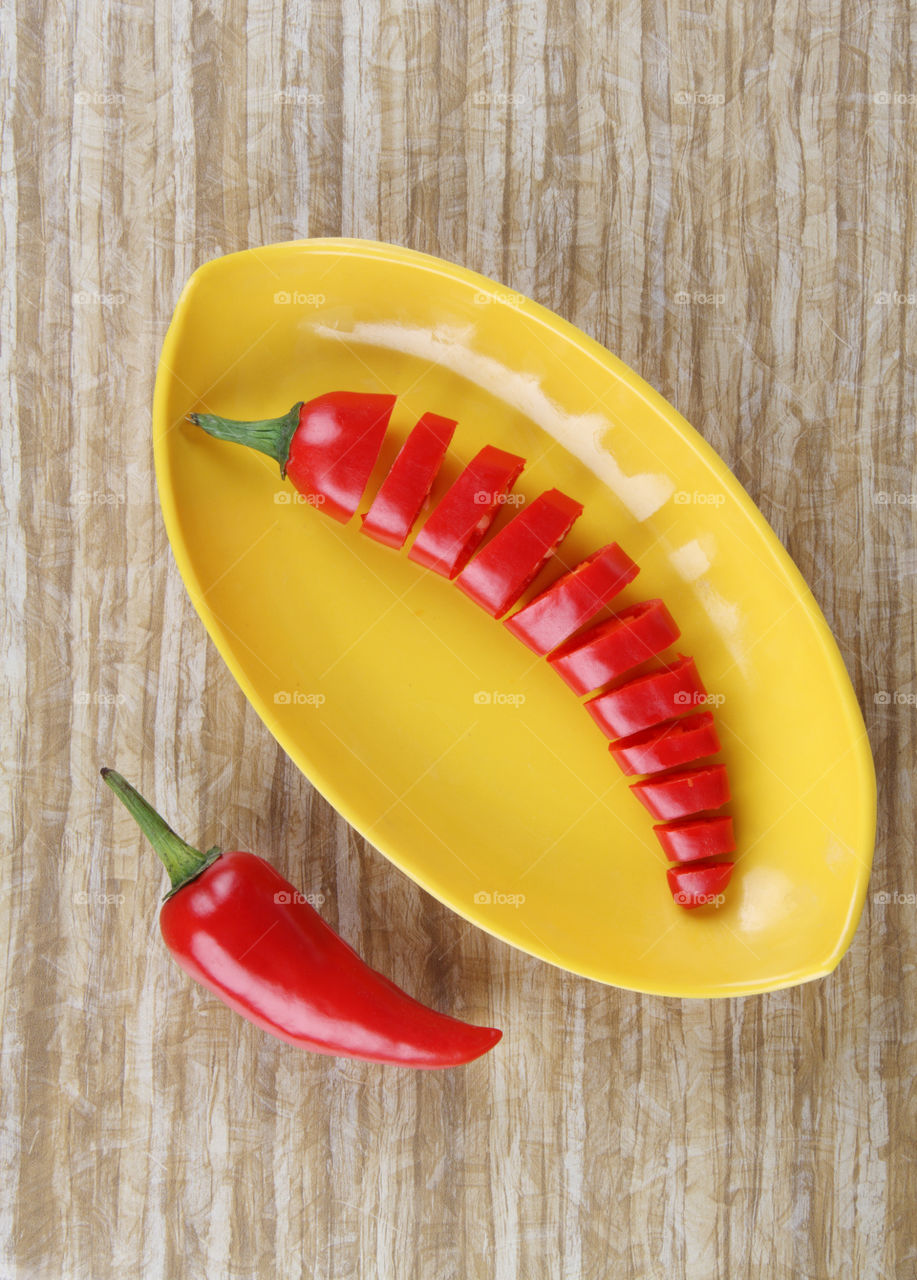 Red hot chilli cut in slices on a wooden background