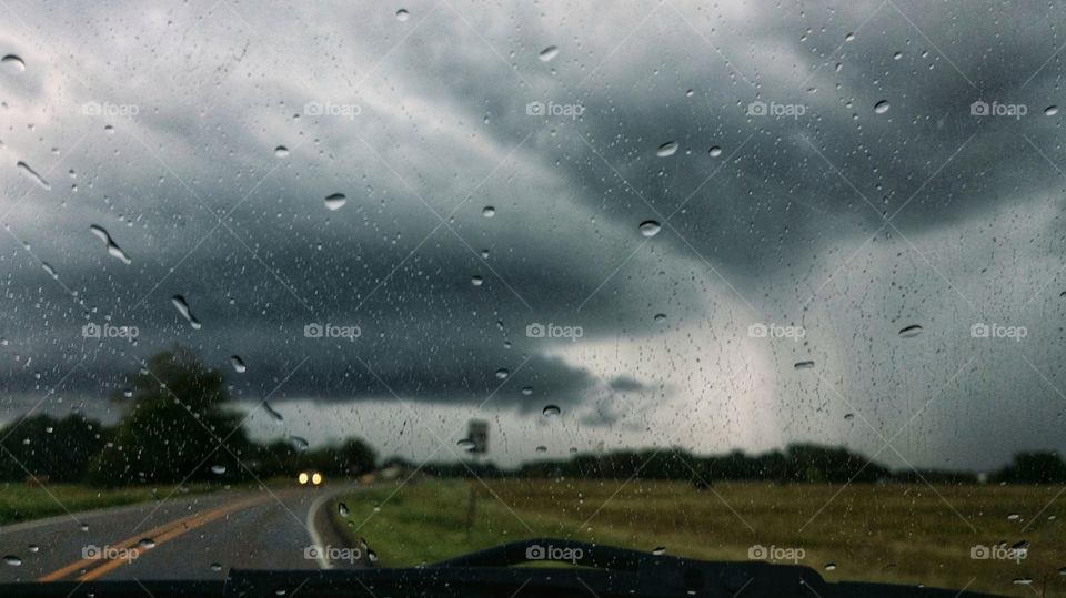 Stormy day driving with headlights on the road ahead