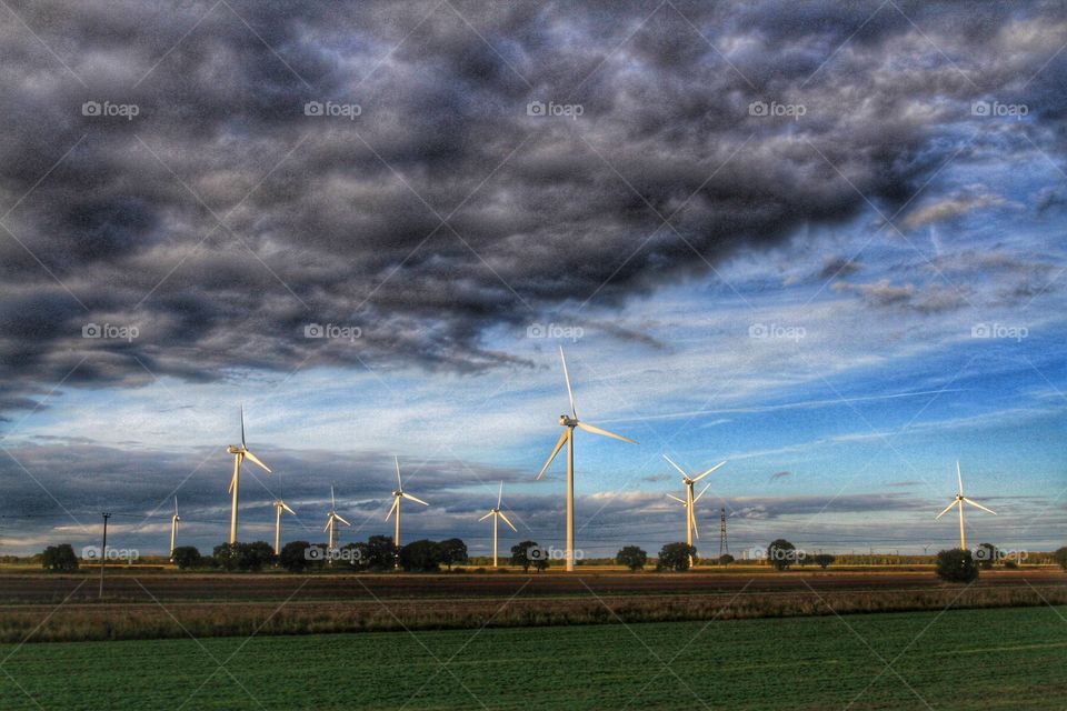 Wind power windmills create electrical energy under a dramatic, stormy sky.