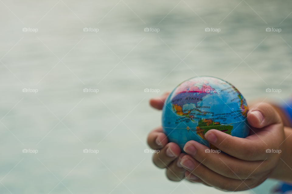 hand holding world sphere, showing North and South America continents