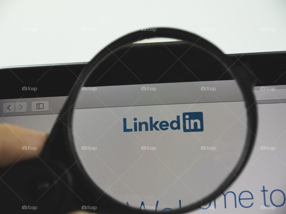 LinkedIn logo on a web page. View of the monitor screen through a magnifying glass